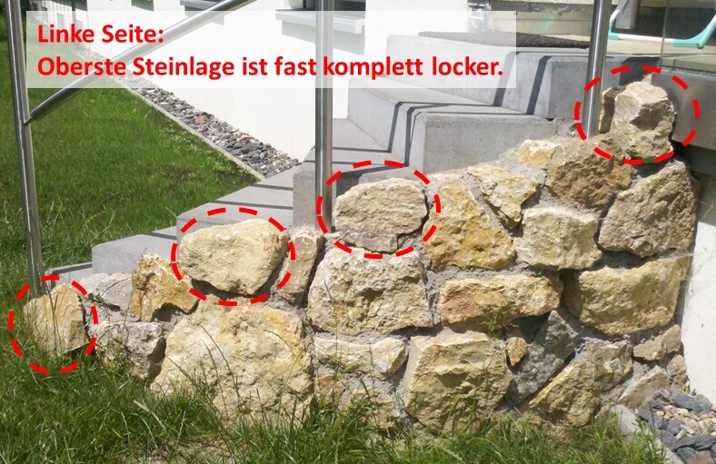 Natursteinmauer mit gelockerten Steinen neben Treppe und Glasgeländer, Hinweis auf Baumängel