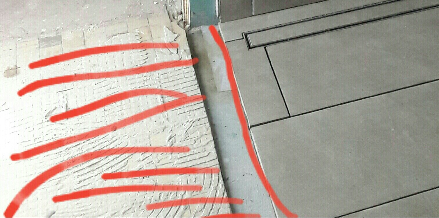 Rote Markierungen kennzeichnen Fuge zwischen Wandputz und Bodenfliesen bei Bauarbeiten
