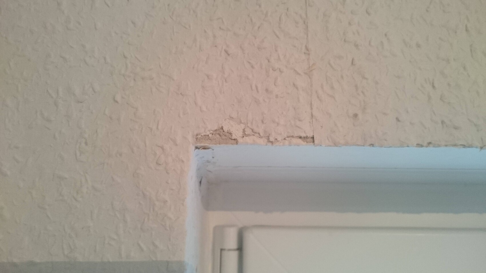 Putzschaden um Türrahmen an Innenwand, beschädigter Verputz