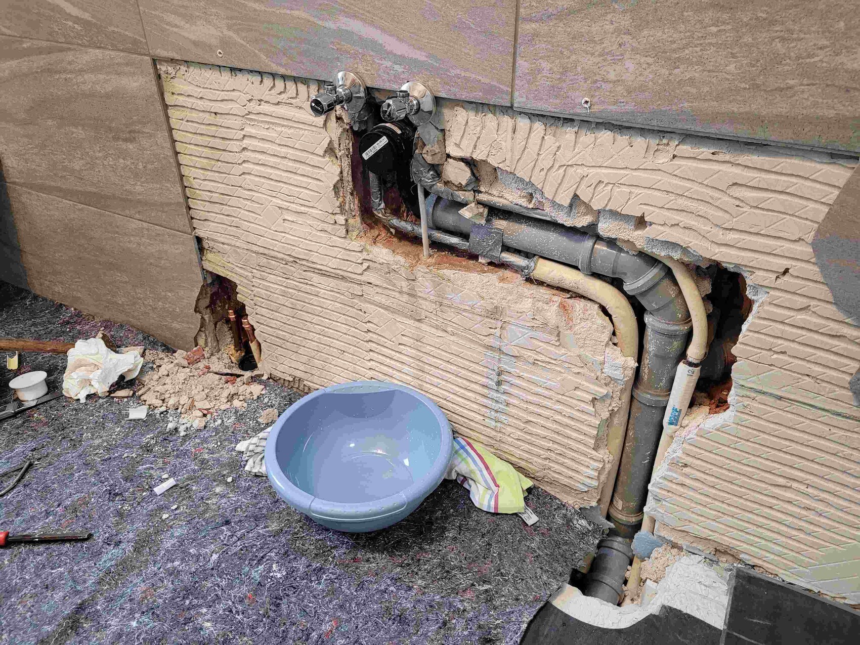 Offene Wand mit Rohren und beschädigtem Putz bei Bauarbeiten