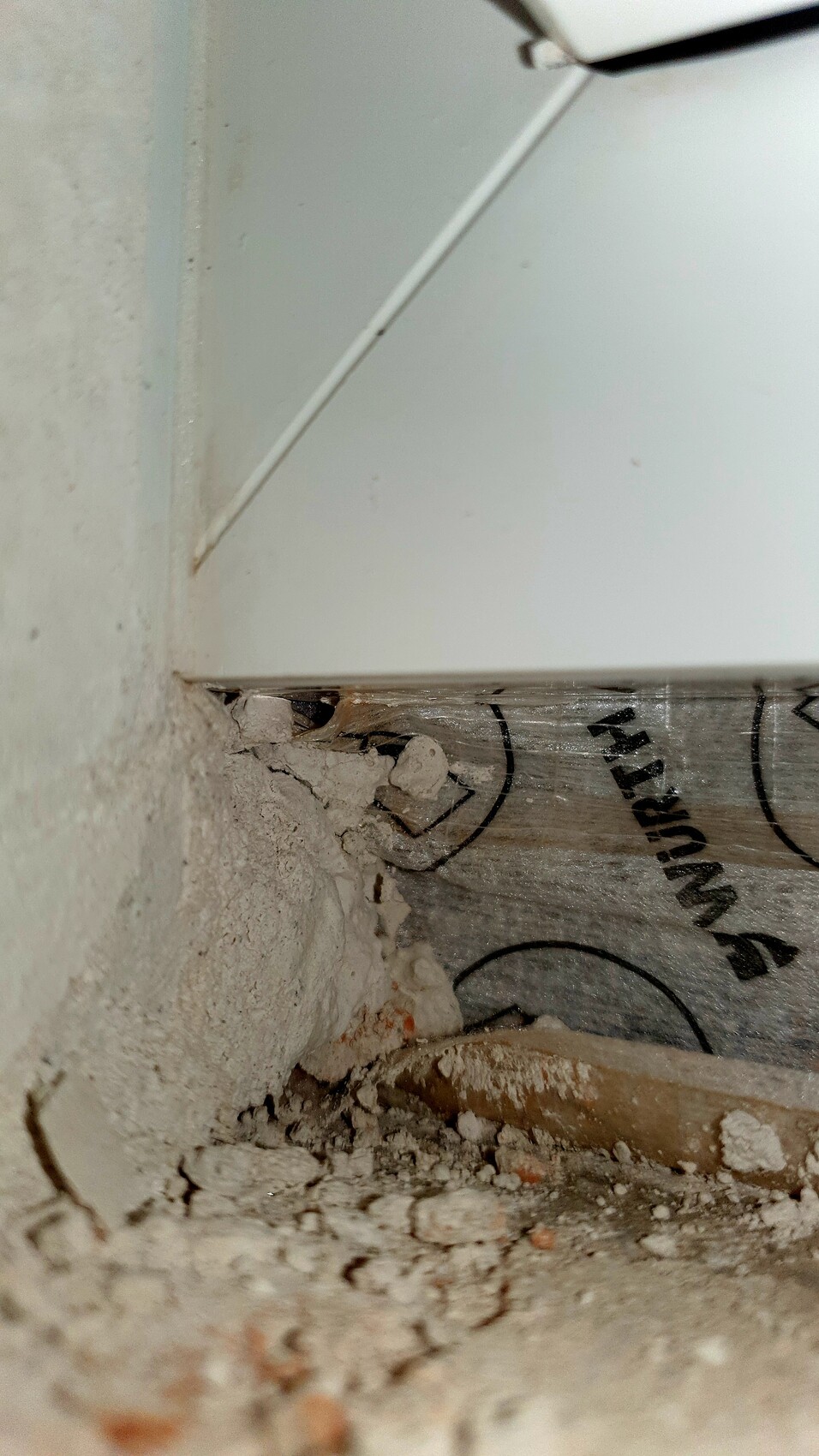 Baustelle: Putzreste, Staub und Schutt an Eckkante von Wand und Boden.