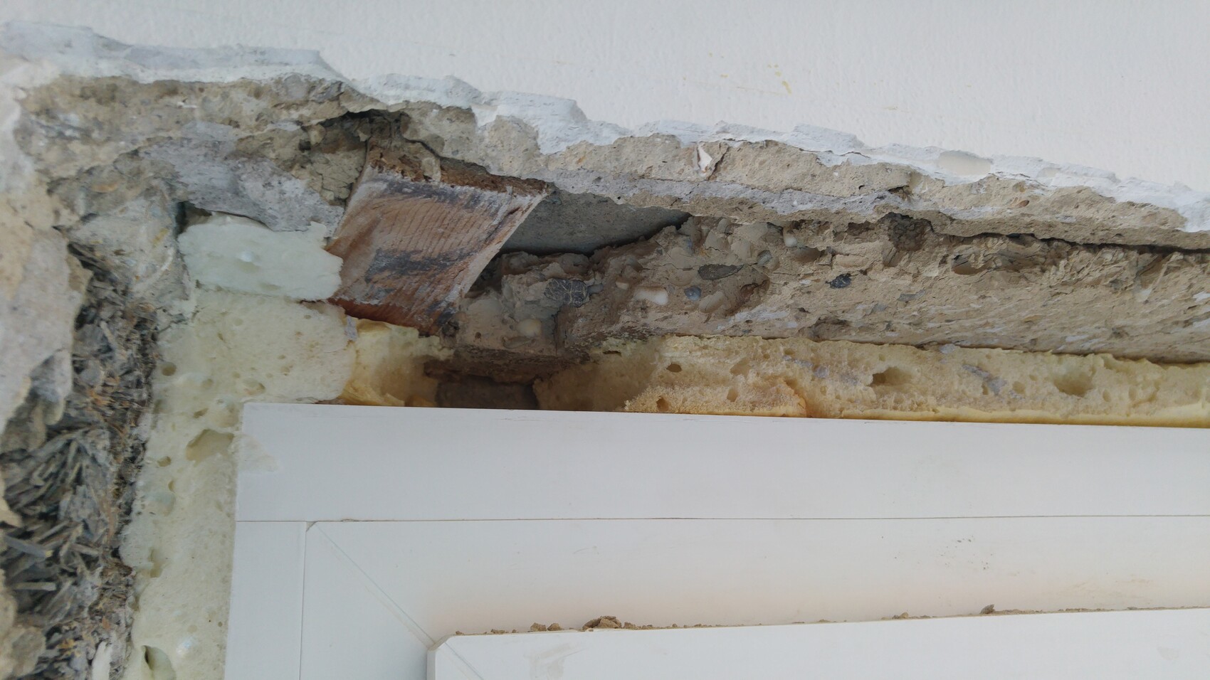Offene Wand mit abplatzendem Putz, Dämmung und Baumaterial sichtbar.