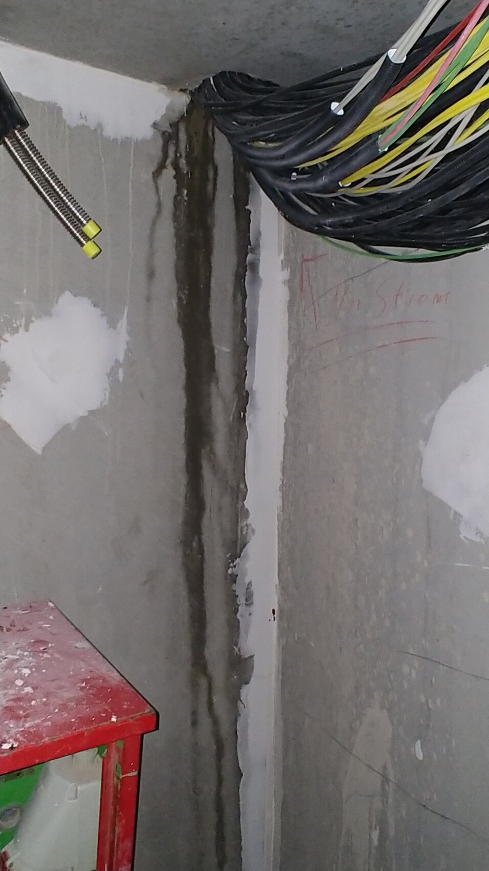 Baustellenraum mit offenen Kabeln an der Wand und Feuchtigkeitsspuren.