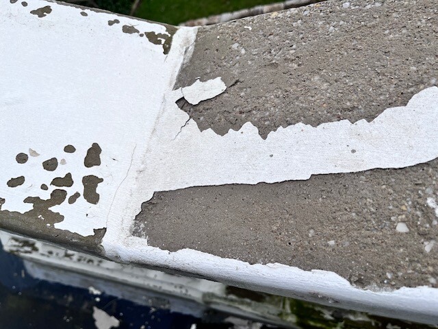 Rissige Betonwand mit beschadigtem Putz und abblatternder Oberflaeche