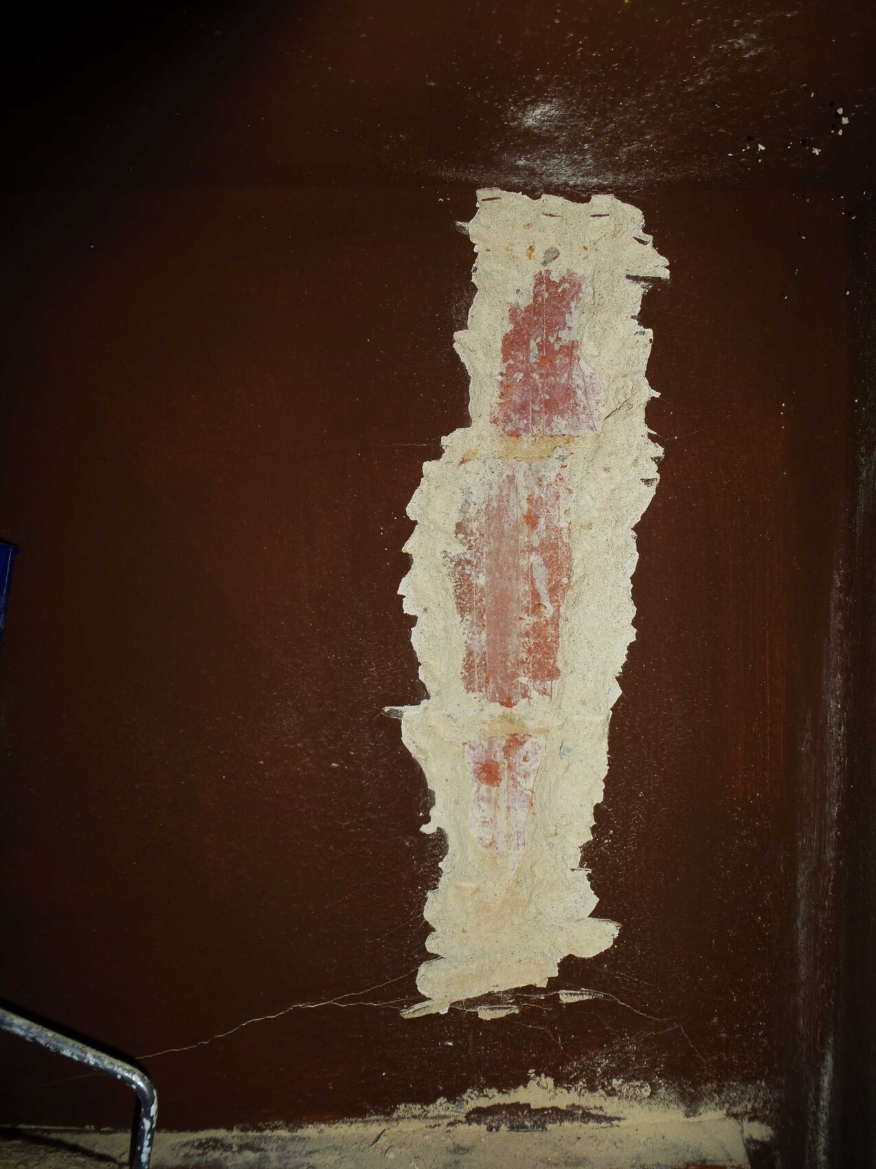 Rissige braune Wand mit ausgebrochener Putzschicht und sichtbarem Mauerwerk