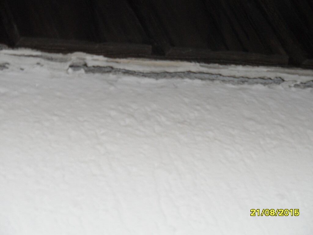 Nahaufnahme einer weißen rauen Wand mit Riss an der Oberkante im Innenraum.