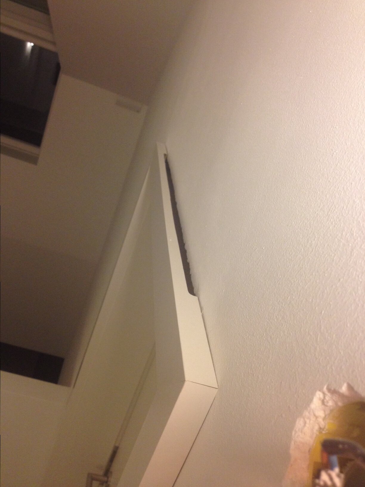 Offener Spalt zwischen Türrahmen und Wand in Innenraum, Putzschaden sichtbar.