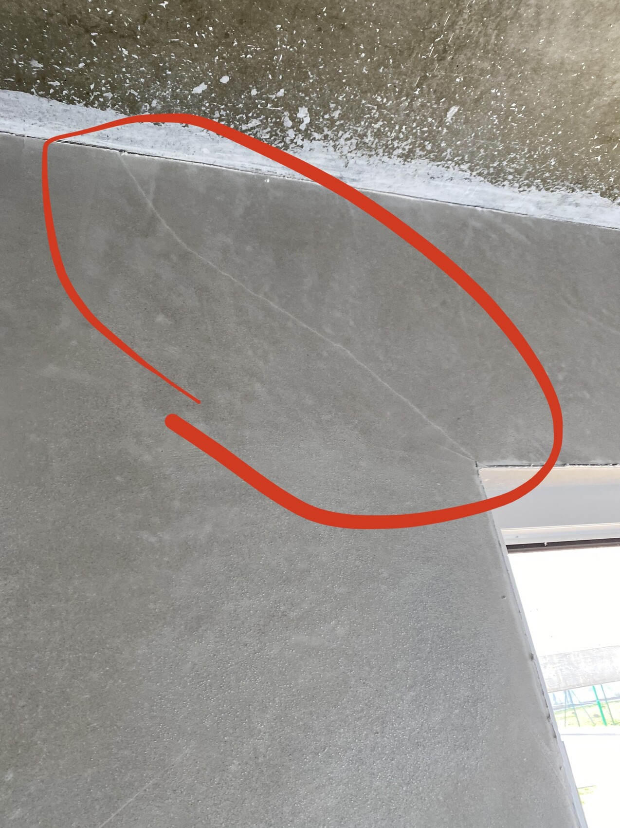 Graue Innenwand nahe der Decke mit feiner Rissspur; rote Markierung hebt den Riss hervor.