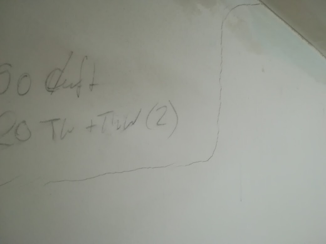 Weiße Wand mit unscharfen handschriftlichen Notizen in einem abgerundeten Rahmen.