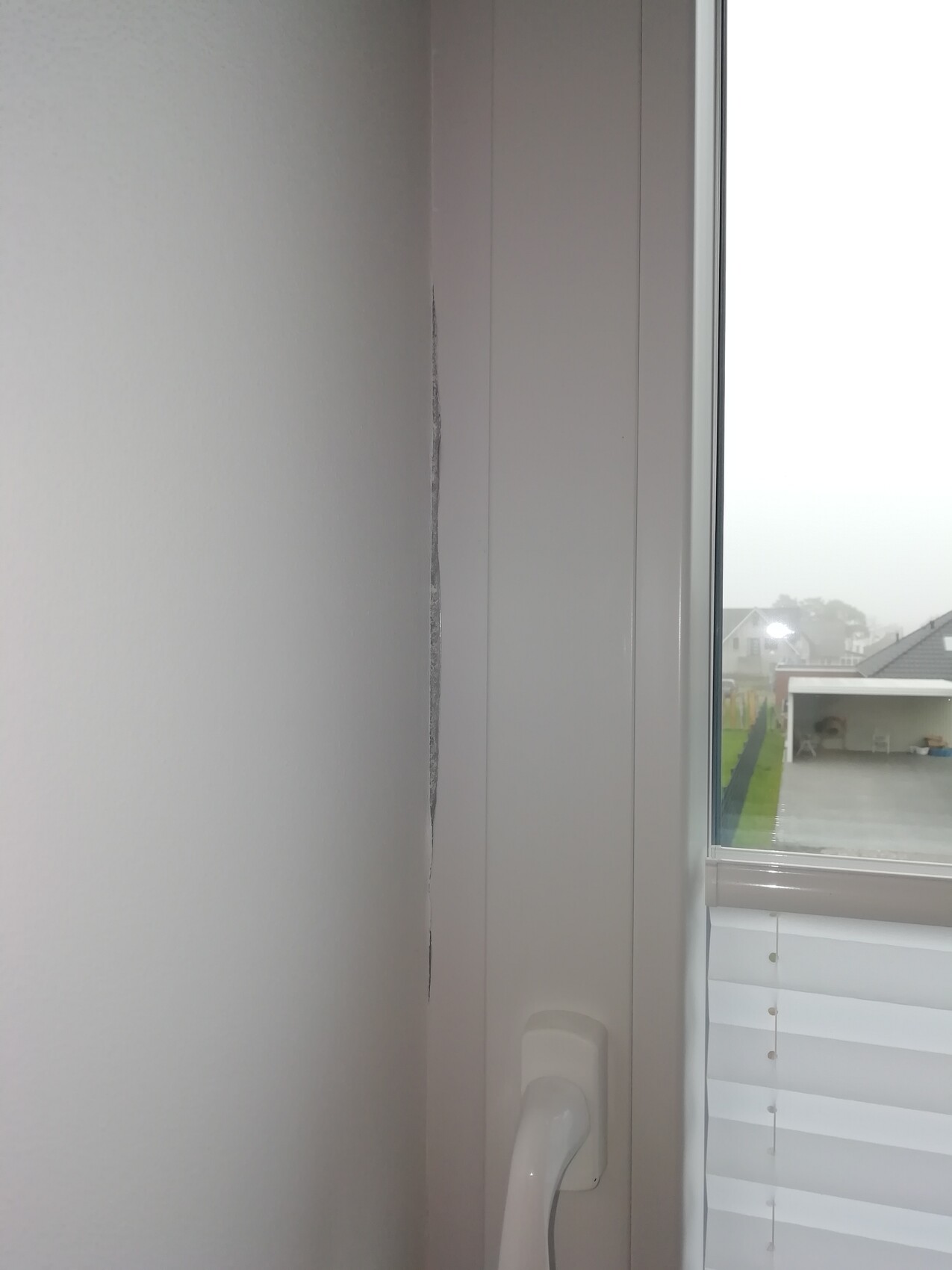Vertikaler Wandriss neben Fensterrahmen im Innenraum, Blick nach außen