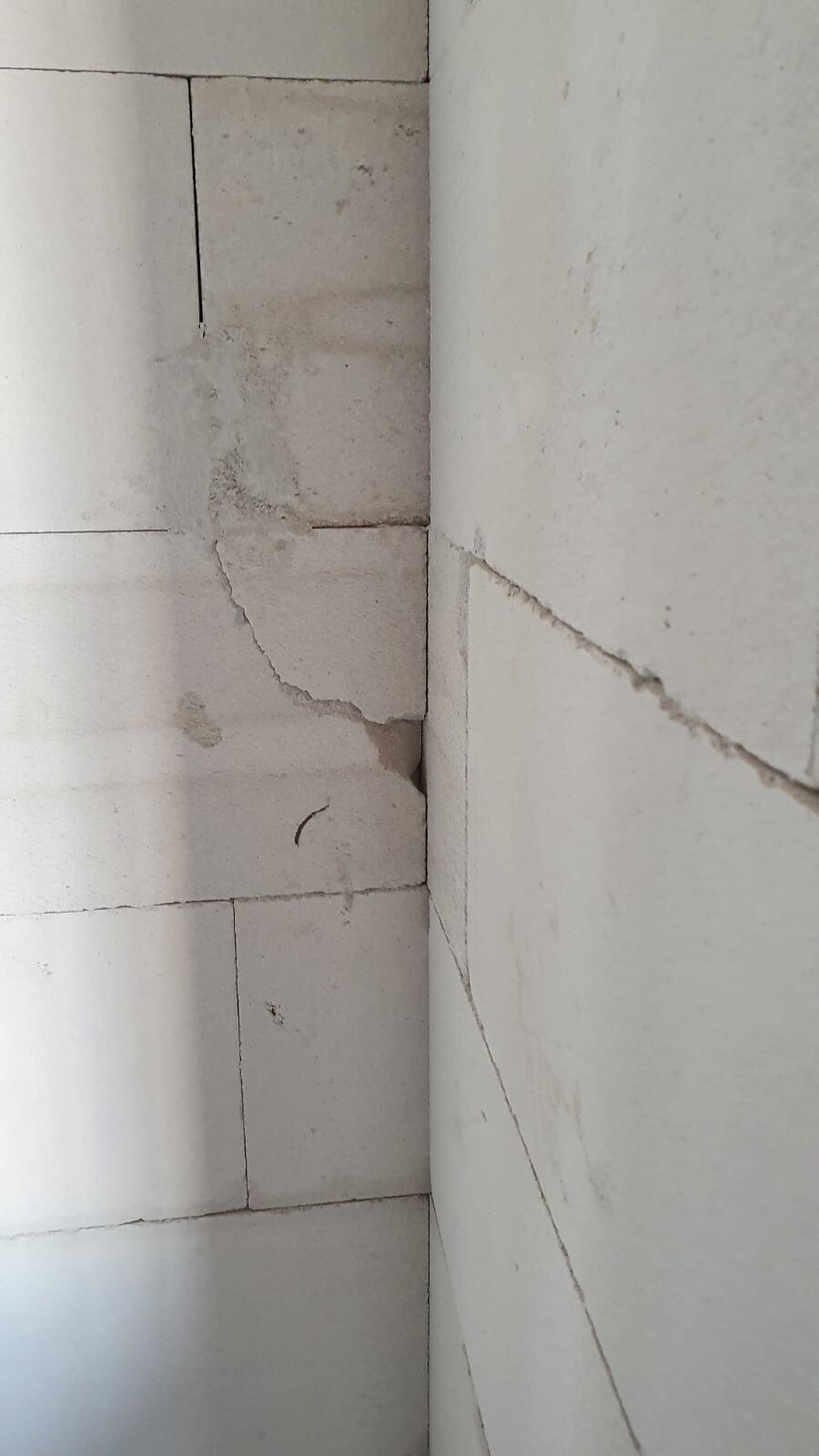 Betonwand-Ecke mit Rissen und Abplatzungen an den Betonblöcken