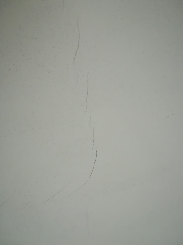 Weiße Wand mit einer feinen vertikalen Risslinie.