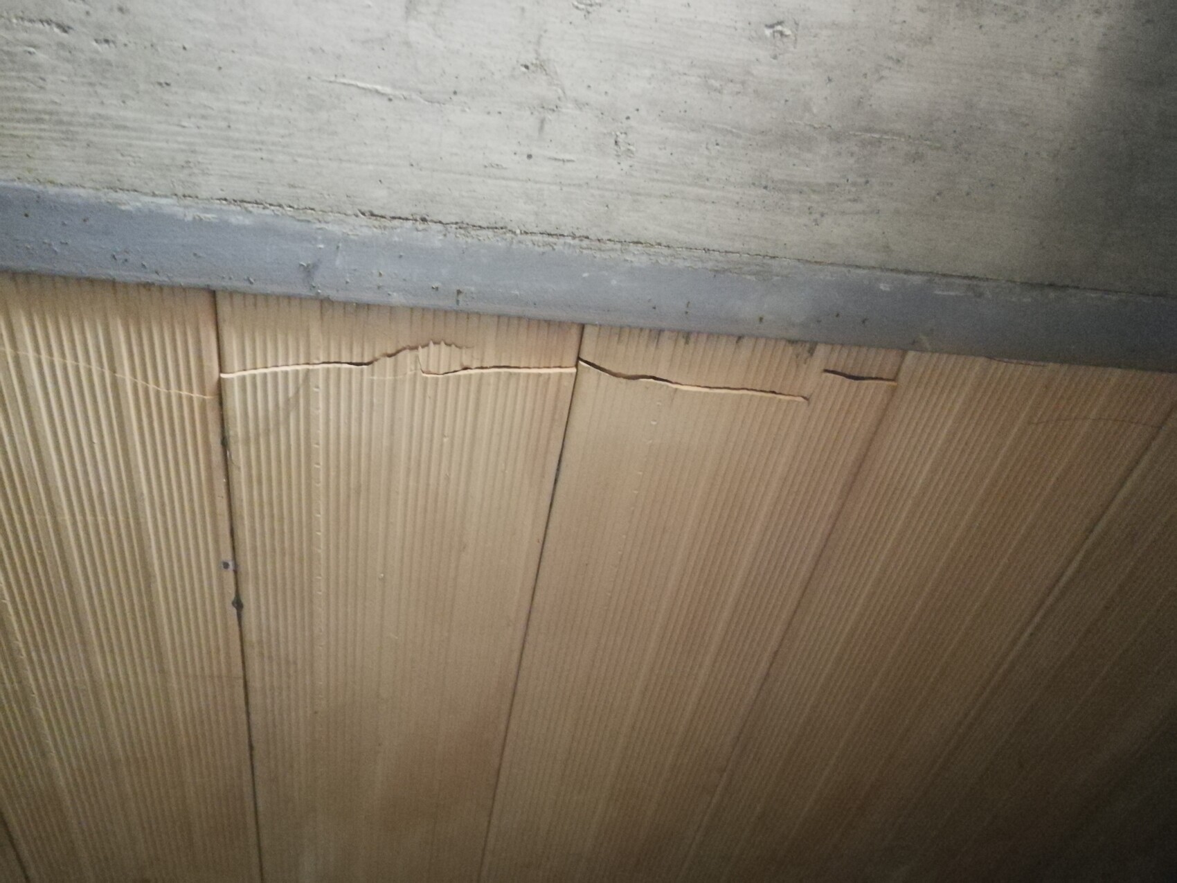 Nahaufnahme einer Wand mit Riss zwischen Beton und Holzverkleidung