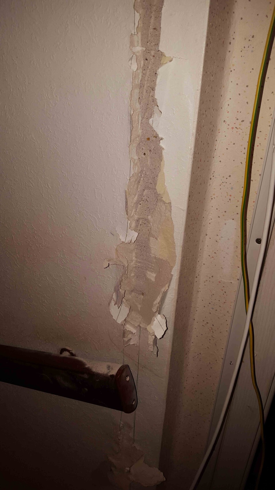 Wand mit abgeplatztem Putz und Rissen, sichtbare Kabel im Innenbereich