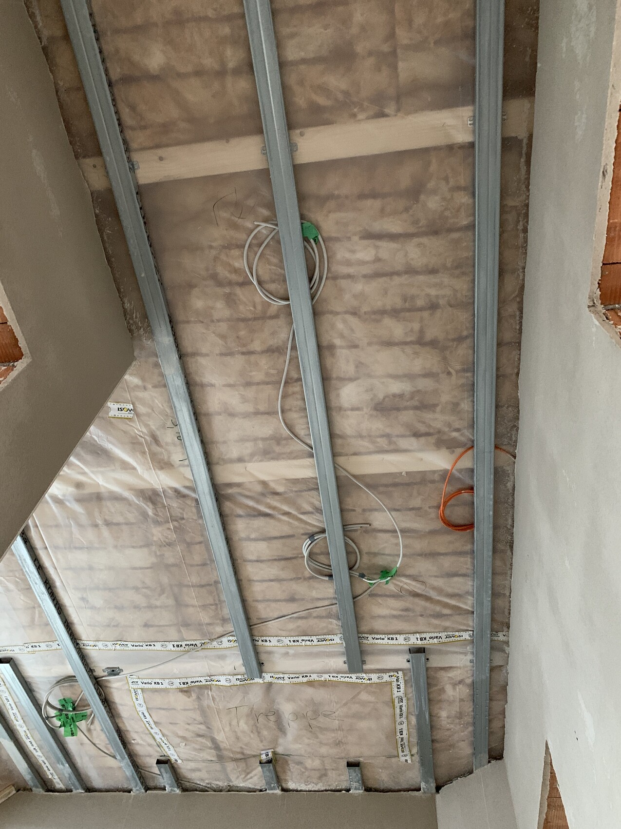 Baustellen-Decke: Metallständer, freiliegende Kabel und Dämmung zwischen Balken.