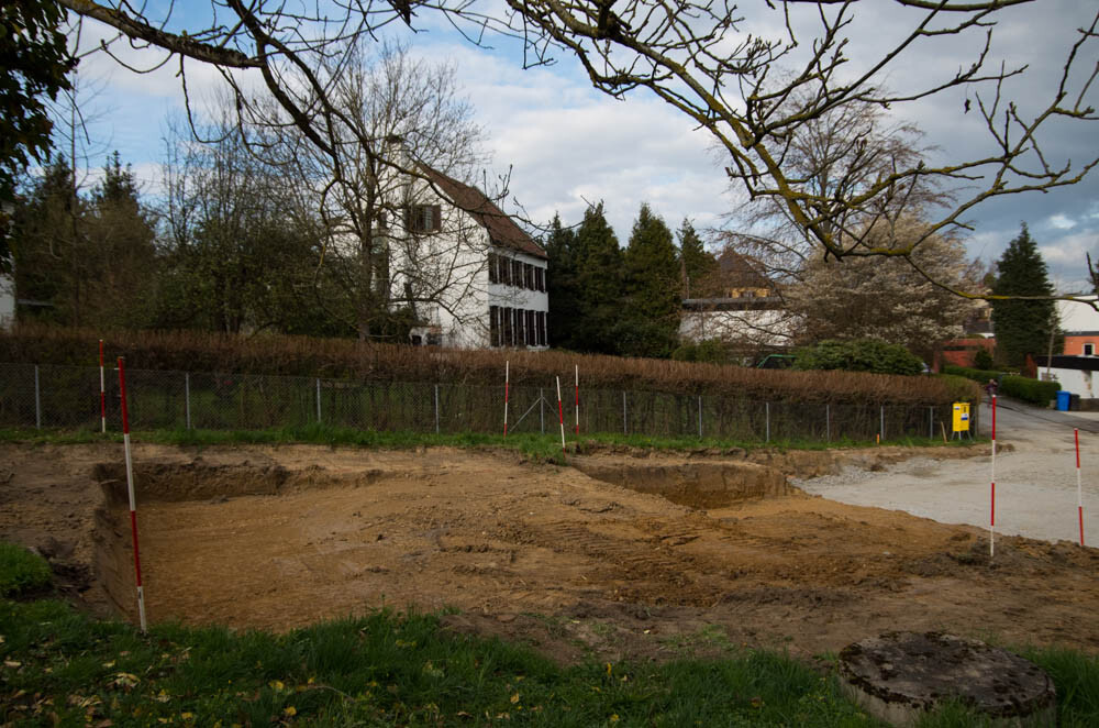 Baustelle mit ausgehobenen Gruben, Absperrungen und Wohnhäusern im Hintergrund