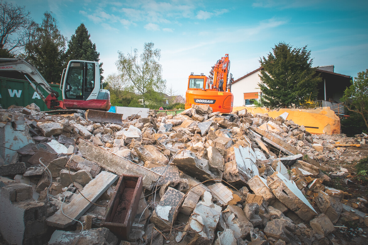 Baustelle mit riesigem Schuttberg und zwei Baggern (orange Doosan im Zentrum)