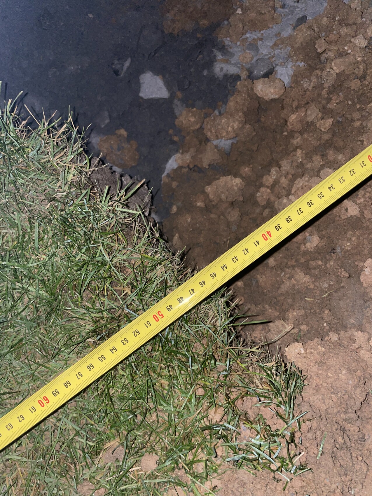 Baustellenboden mit Messband auf Erde und Gras, Erdarbeiten sichtbar