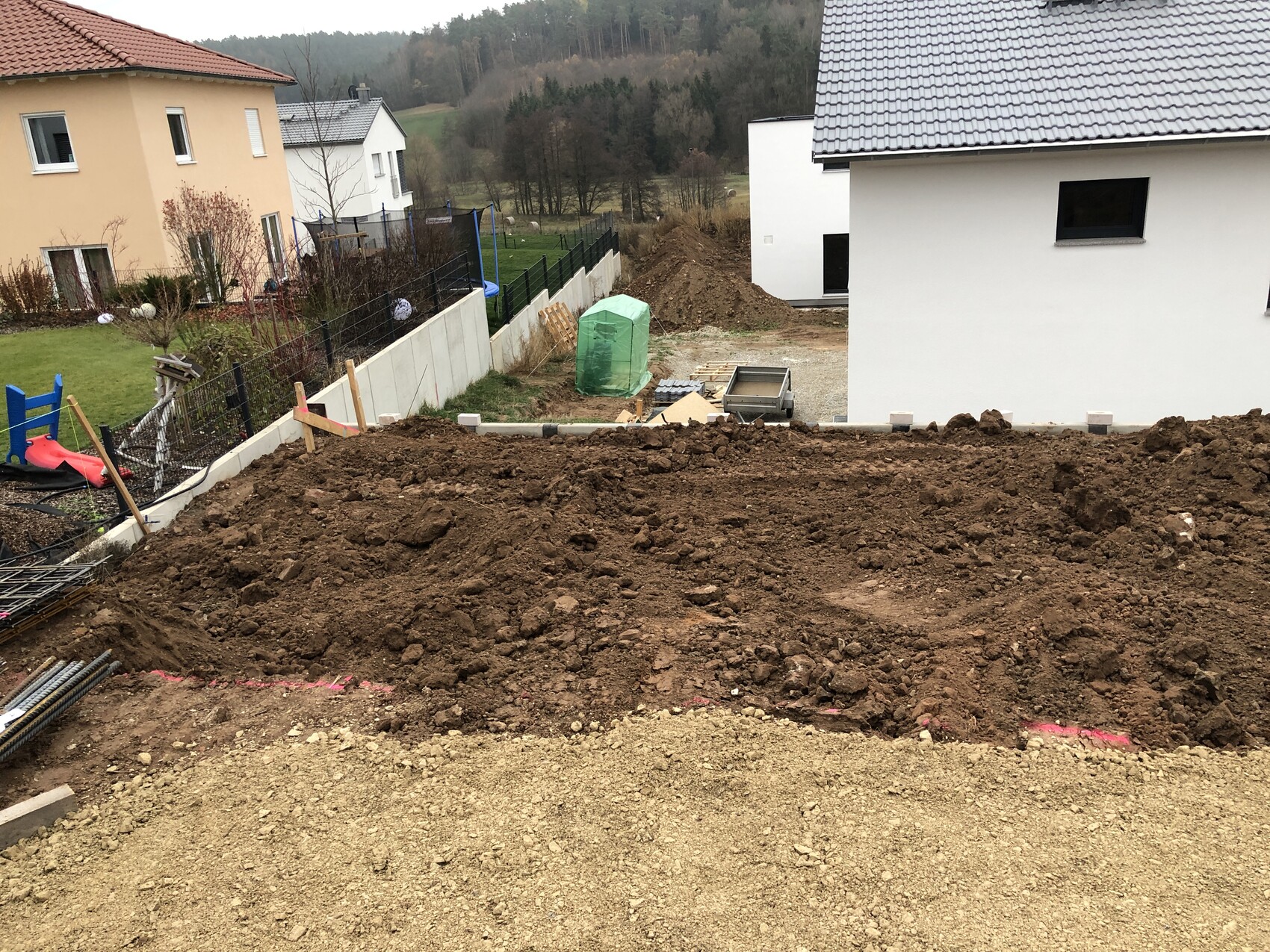 Baustelle im Hof: freigegrabene Erde, Baugrube, Bauzubehör und zwei Häuser im Hintergrund.