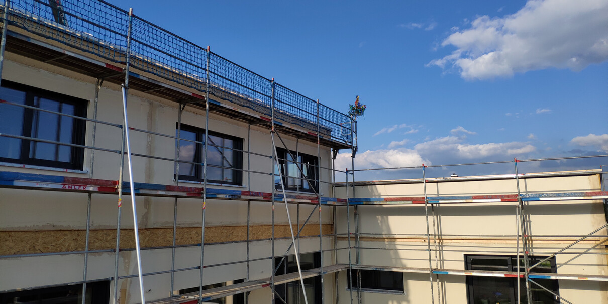 Gerüst um eine Gebäudefassade während Bauarbeiten, Fensterfronten, blauer Himmel