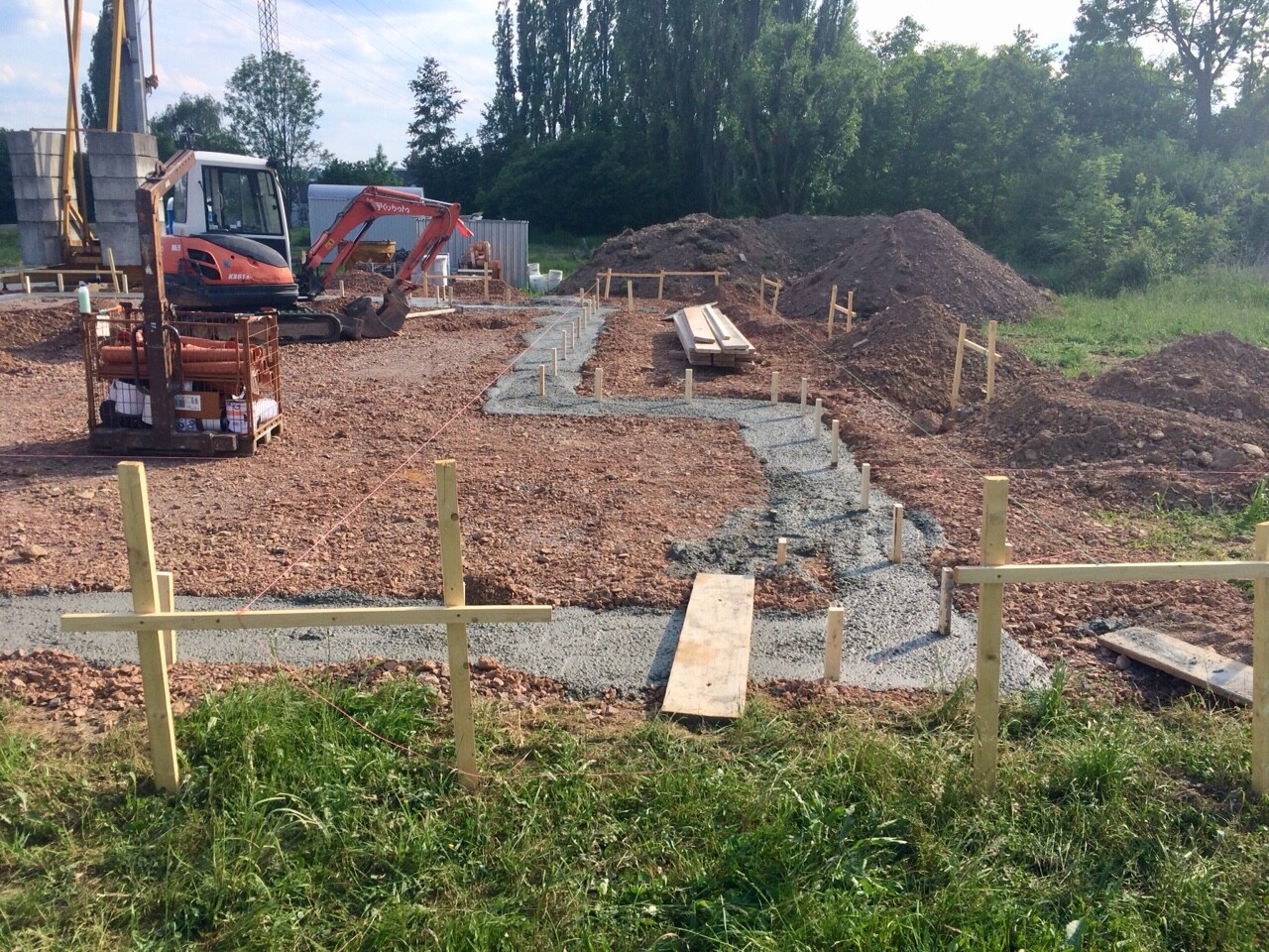 Kleine Baustelle mit Minibagger, Kiesweg, Holzpfosten und Erdarbeiten