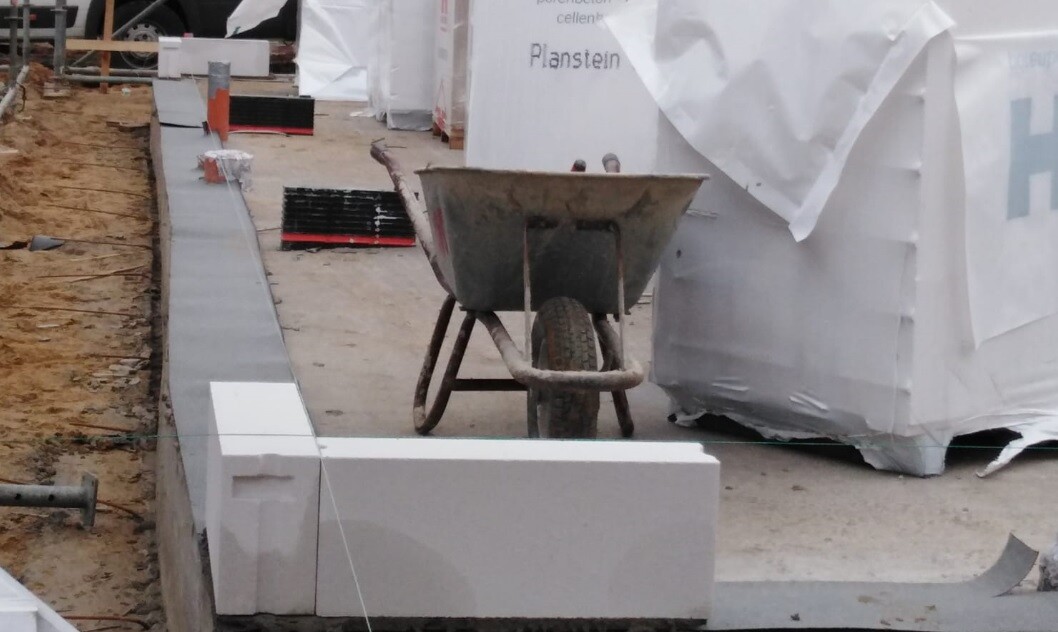 Baustelle mit Schubwagen vor Fundamentbauteilen und Bauplatten