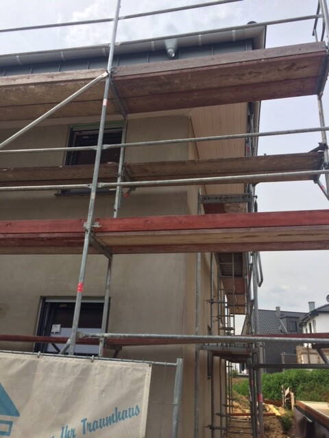 Außenbaustelle mit Gerüst um einen Neubau, mehrstöckiges Gebäude im Rohbau.