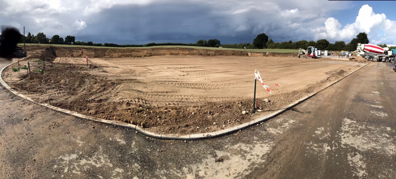 Große Baustelle mit ausgehobenen Erdarbeiten, Baggern und Betonmischer am Rand