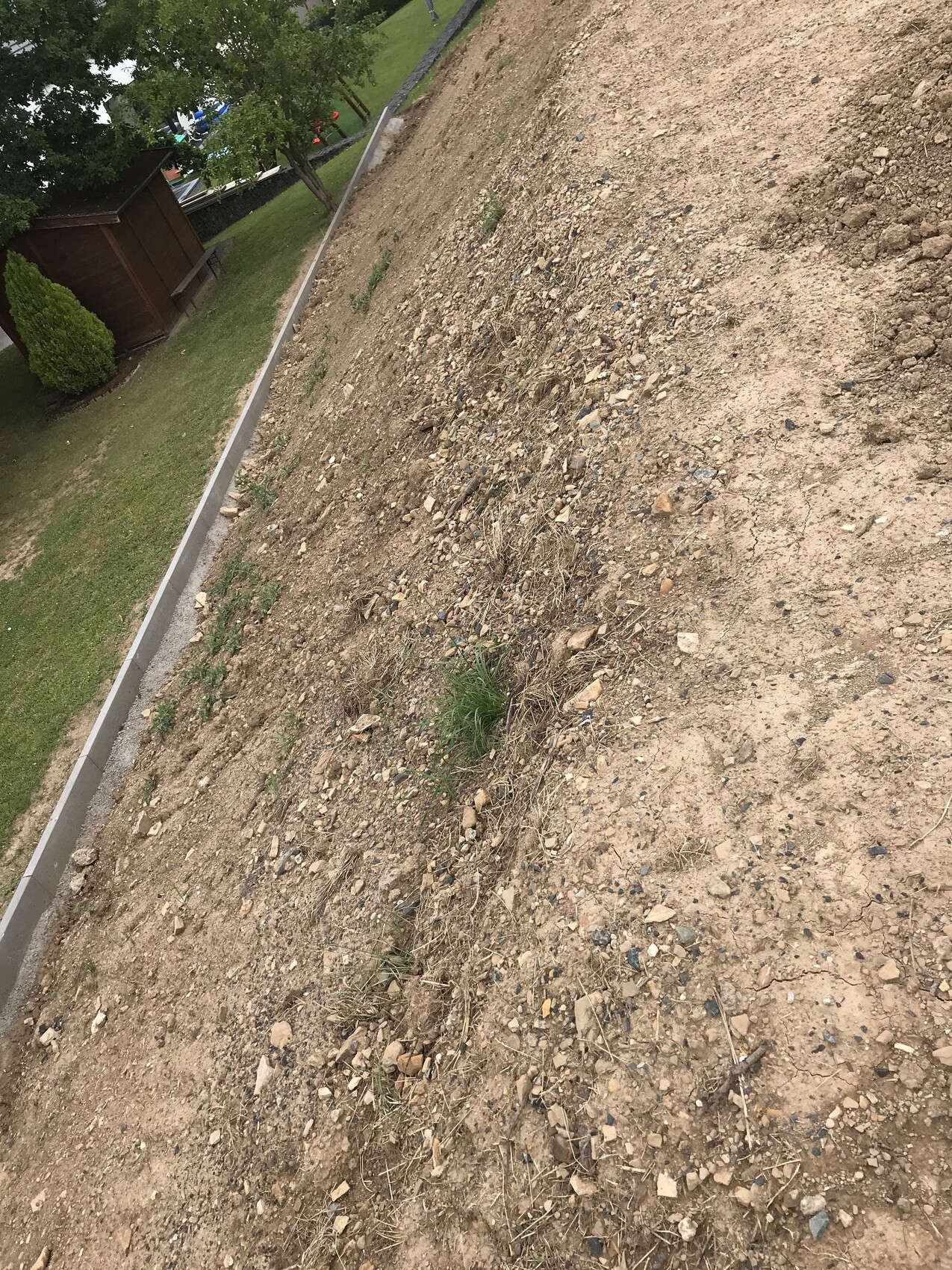 Hang mit losem Erdreich und Kies neben Begrenzungsmauer auf einer Baustelle