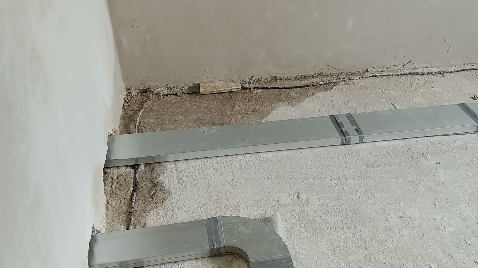 Baustelle mit Metall-Luftkanalrohren auf staubigem Boden im Bauprozess