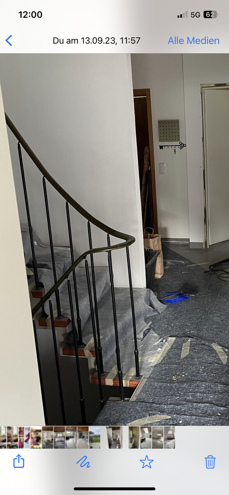 Innenaufnahme eines Treppenhauses: dunkles Geländer, gewendete Stufen, Bauutensilien auf dem Boden.