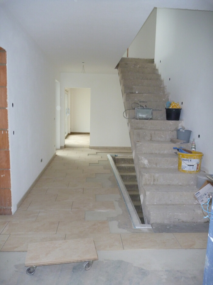 Heller Flur im Innenausbau mit unfertiger Treppe und Bauwerkzeugen auf Baustelle