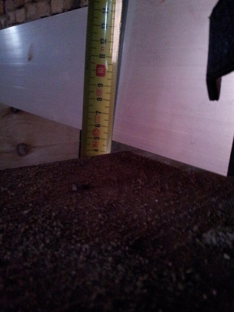 Messband steht senkrecht an einer weißen Wand neben Erde auf einer Baustelle.