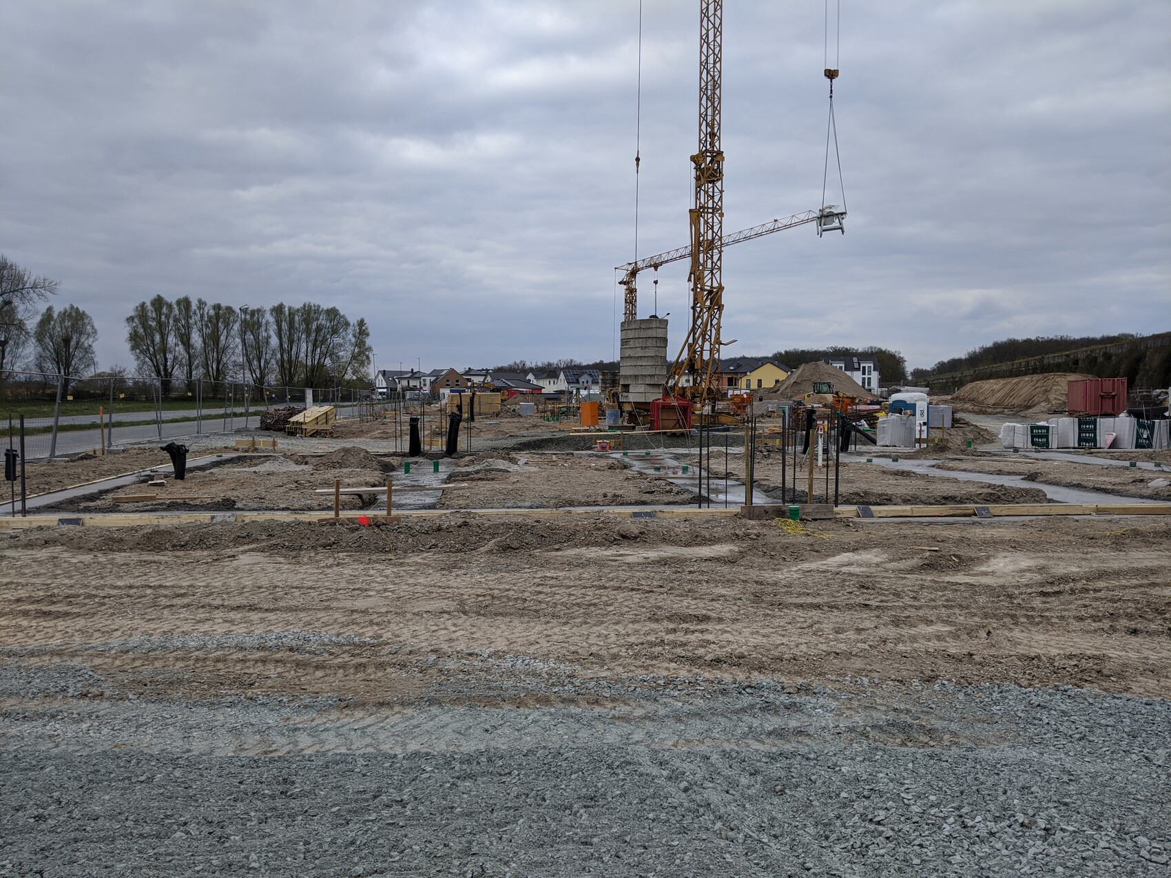 Große Baustelle mit Kran, Erdarbeiten und Wohnhäusern im Hintergrund.