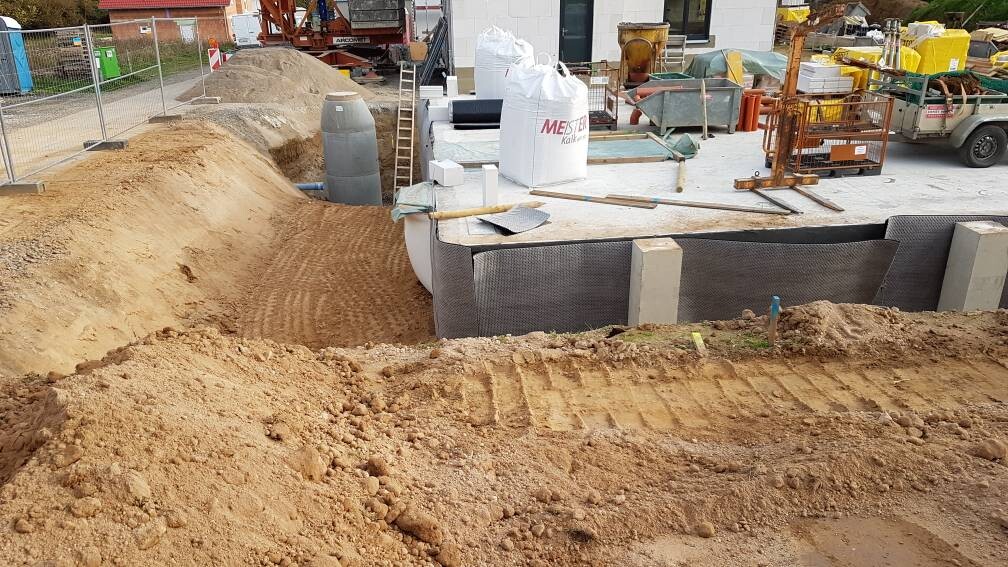 Baustelle: Graben, Erdarbeiten, Fundamentbereich mit Dämmungstechnik und Baumaterialien.