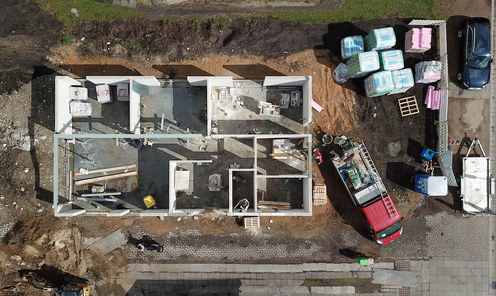 Vogelperspektive: Baustelle mit Rohbau, Baustoffen, LKW und Bauwerkzeugen