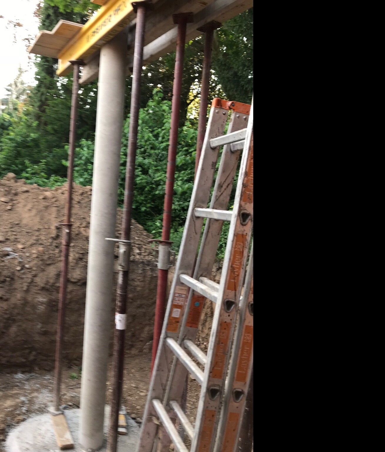 Baustelle mit Stützrohren, Leiter und Erdgrube; Holz- und Metallkonstruktion