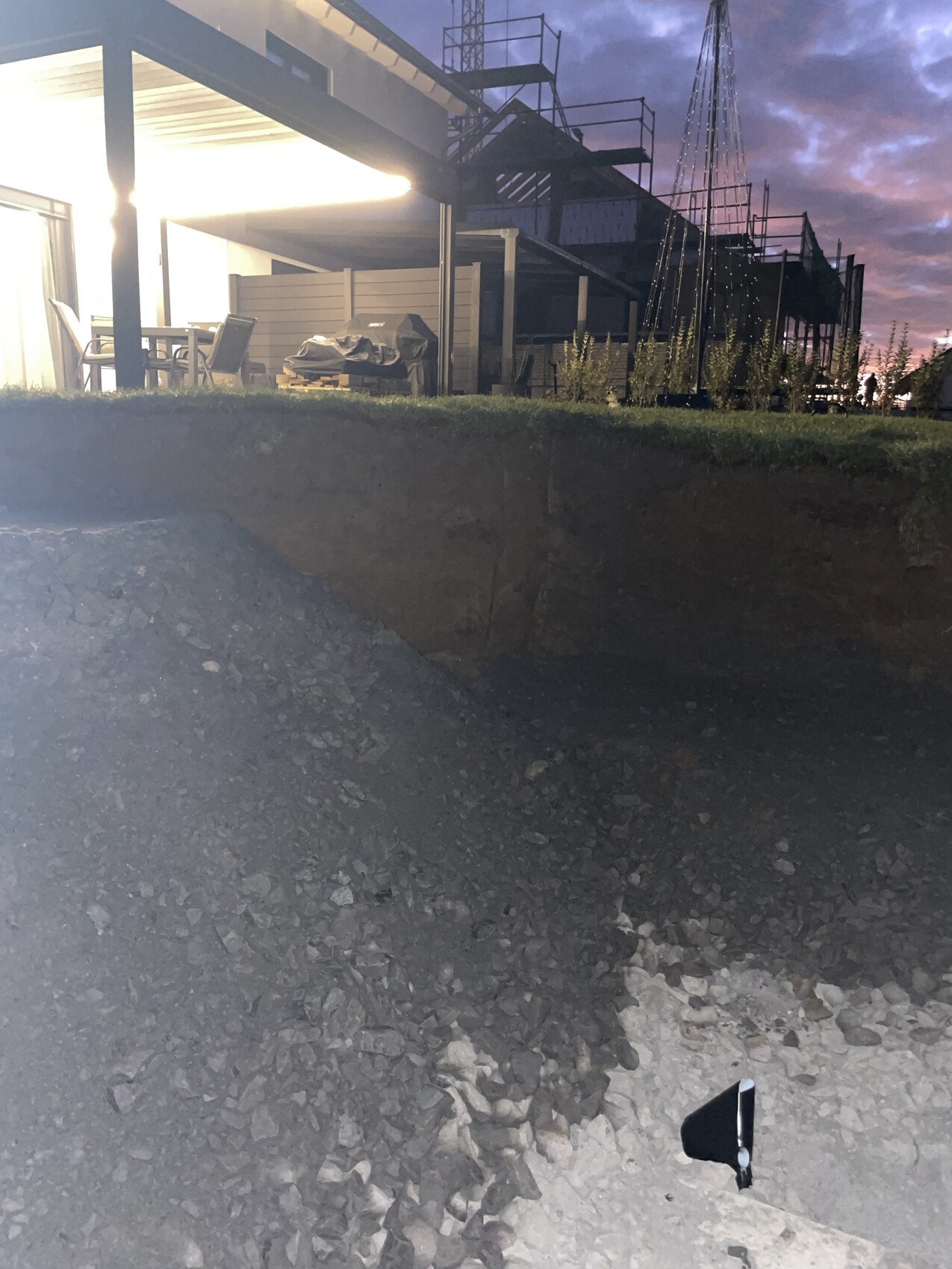 Rohbau Baustelle mit Fundamentarbeiten, Gerüst und Baugeräten bei Abendlicht.