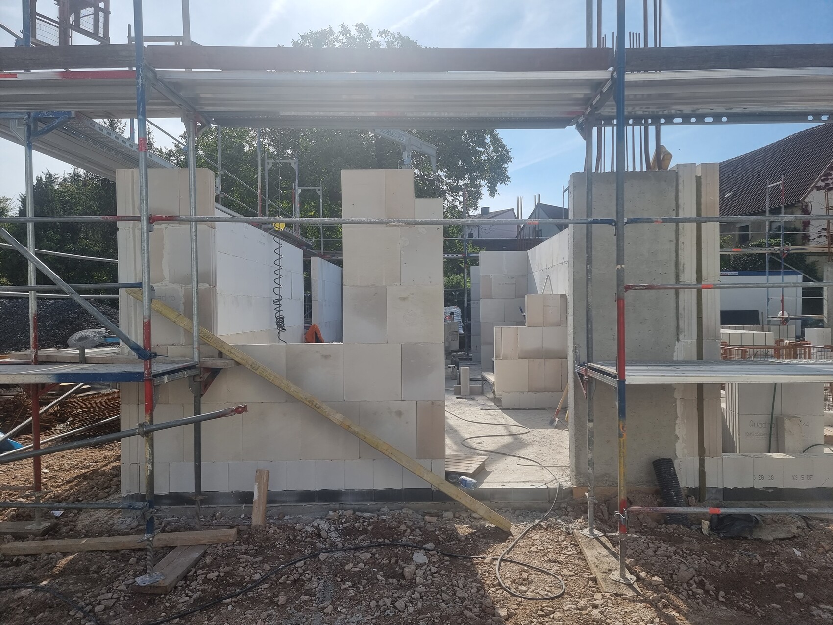 Baustelle mit Gerüst und weißen Porenbetonblöcken, Innenbereich im Aufbau.