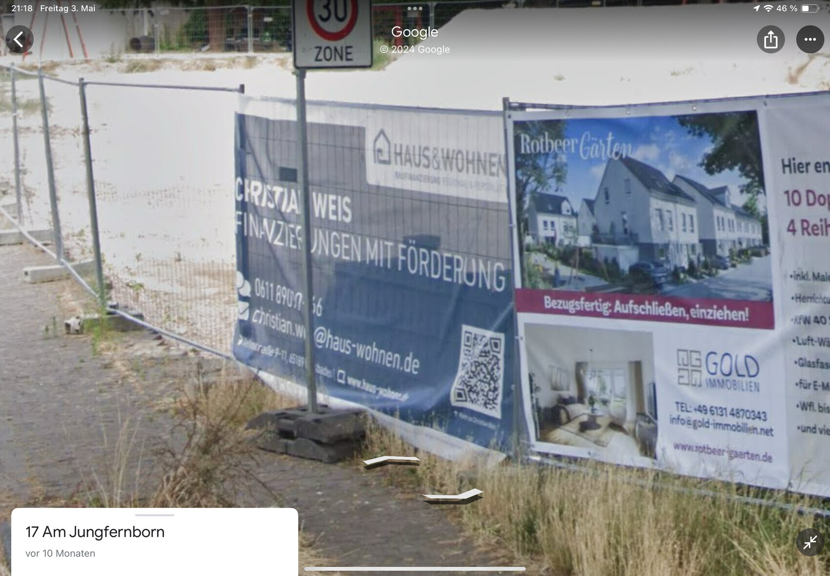 Baustellenzaun mit Werbebannern für Immobilienprojekt, 30er-Zone Schild im Hintergrund