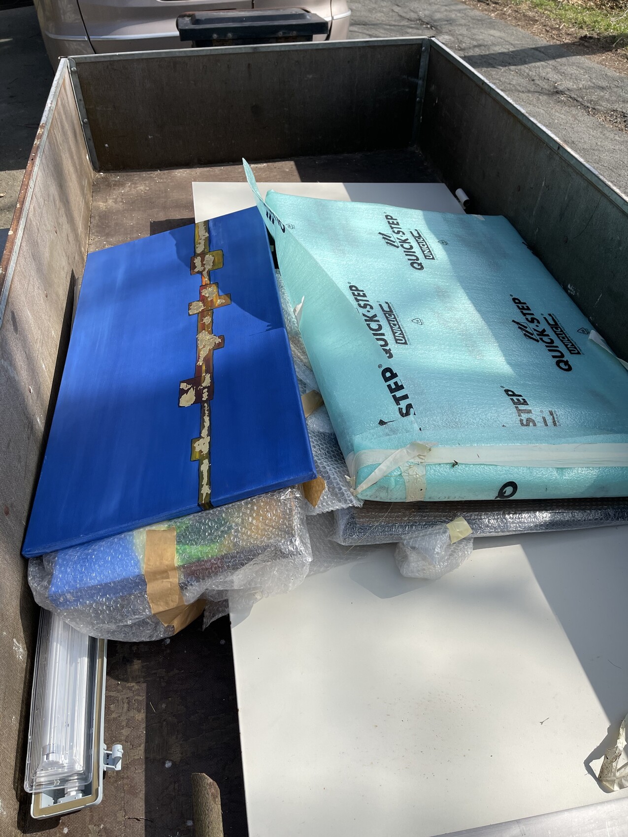 Ladefläche mit Baumaterialien: blaue Holzplatte, hellblaue Dämmplatte und Luftpolsterfolie.