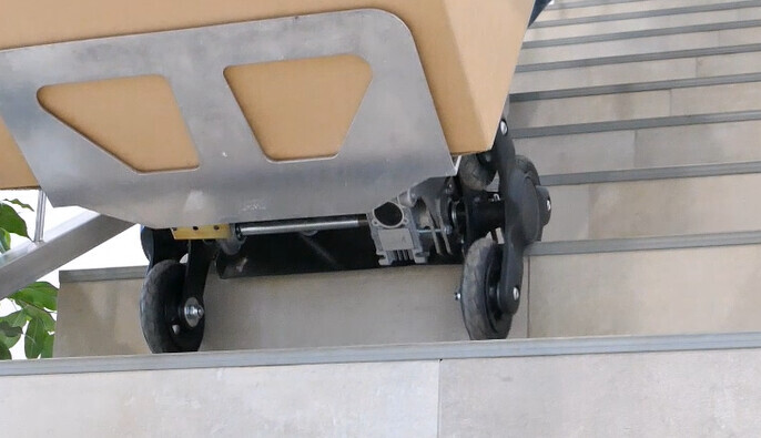 Baustellenwagen mit Behälter auf einer Treppe, metallischer Rahmen und Räder sichtbar