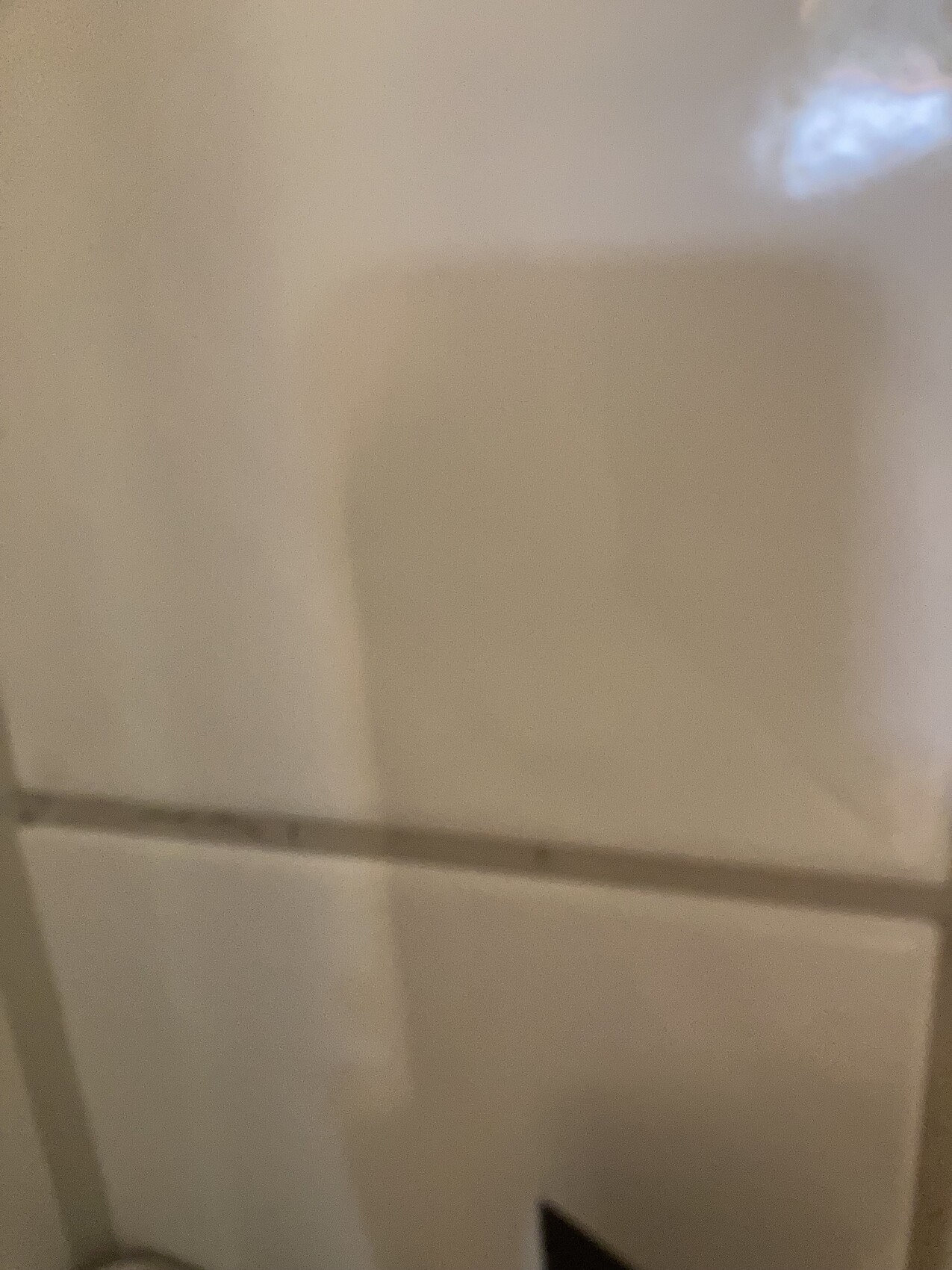 Nahaufnahme einer beigen, glatten Wand- oder Schrankoberfläche mit sichtbarer Fuge.