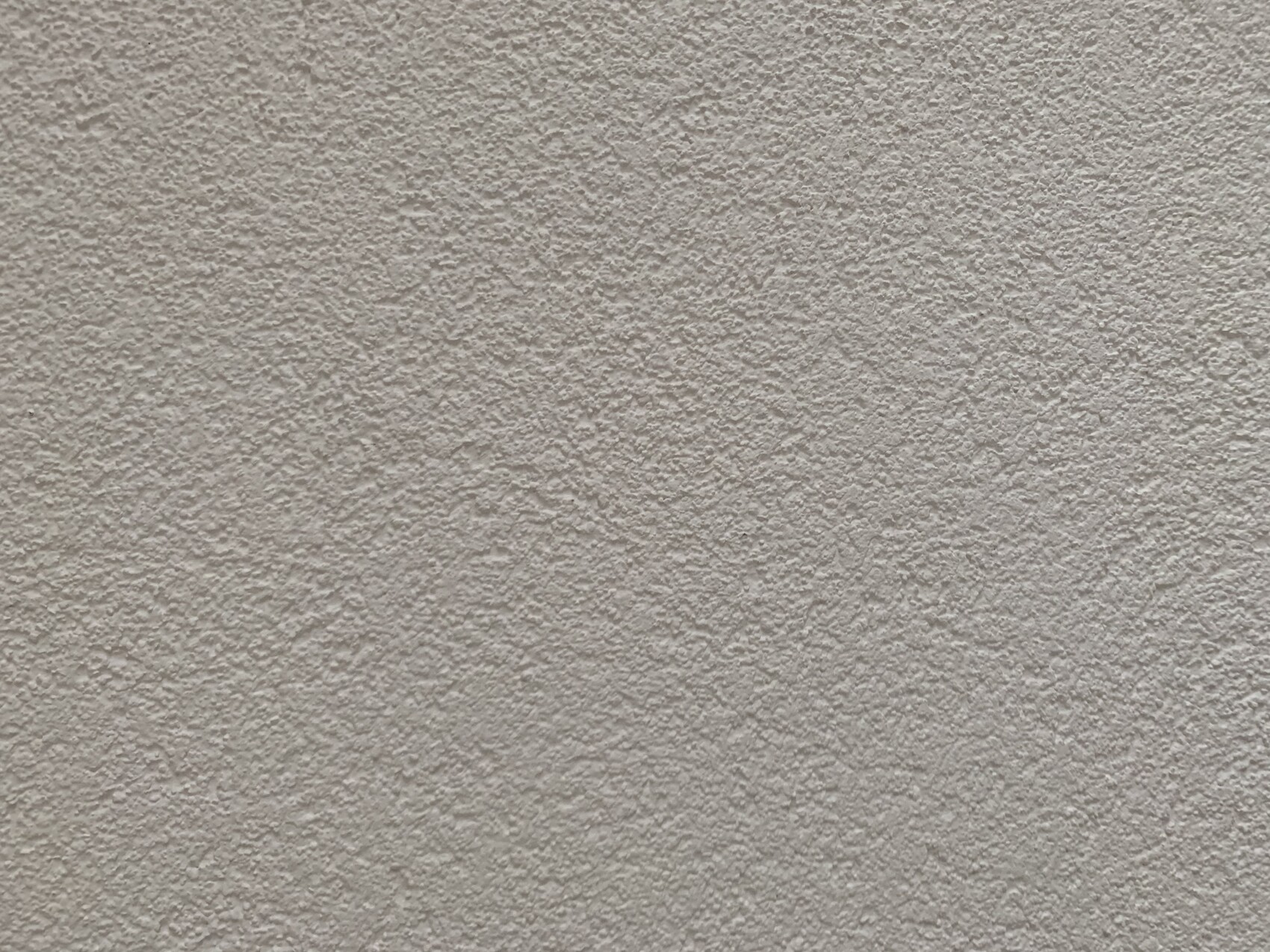 Beige Putzwand mit grober Struktur.