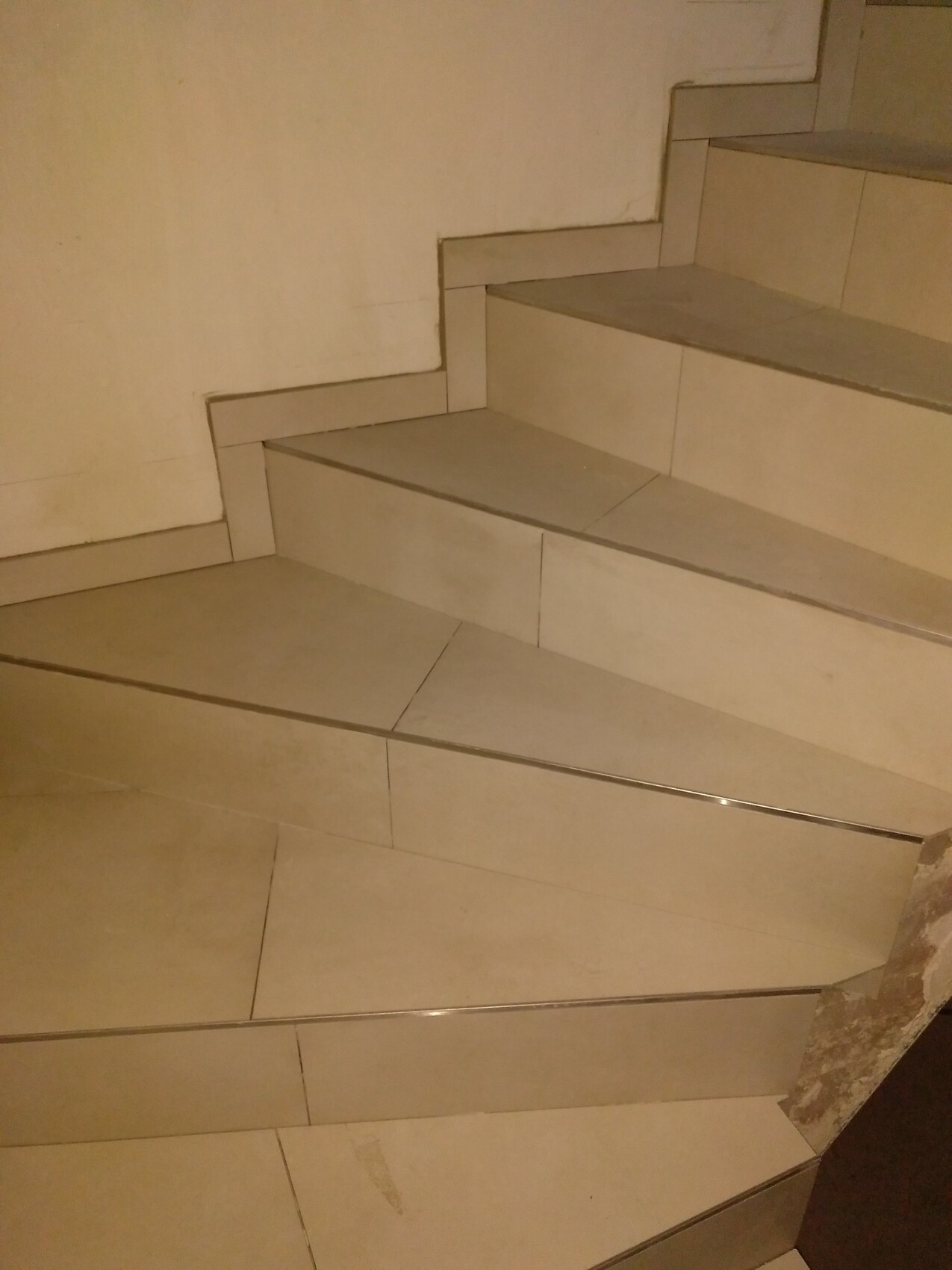 Helle Innen-Treppe aus Steinfliesen mit mehreren Stufen und seitlichen Wänden.