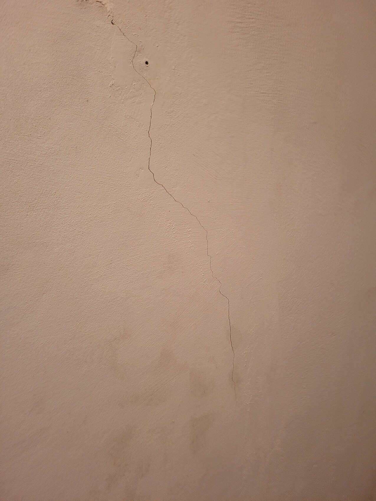 Beige Wand mit sichtbar langem Putzriss im Innenraum