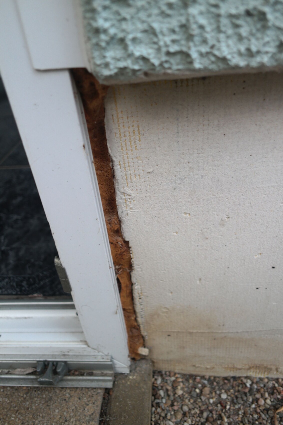 Außenwand-Ecke mit freiliegter verrotteter Holzkonstruktion zwischen Türrahmen und Wand.