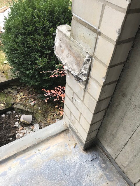 Beschädigte Außenmauer mit Bruchstücken an der Fundamentkante eines Gebäudes