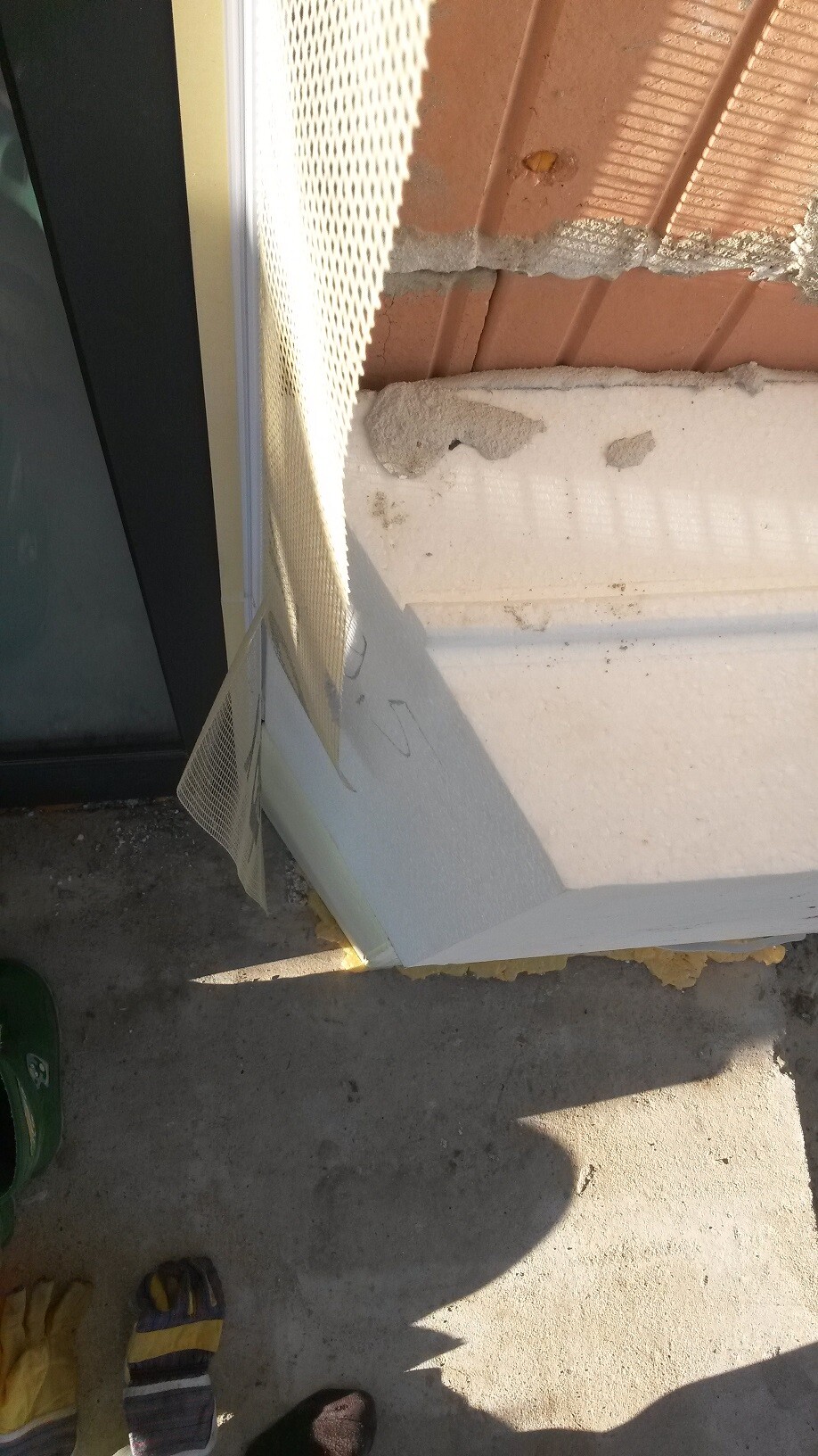 Außenbereich eines Fensters mit beschädigter Dämmung und bröckelnder Wandverkleidung