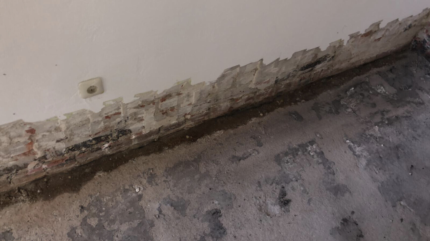 beschädigte-wand-mauerwerk-unterputz-im-wohnzimmer.png